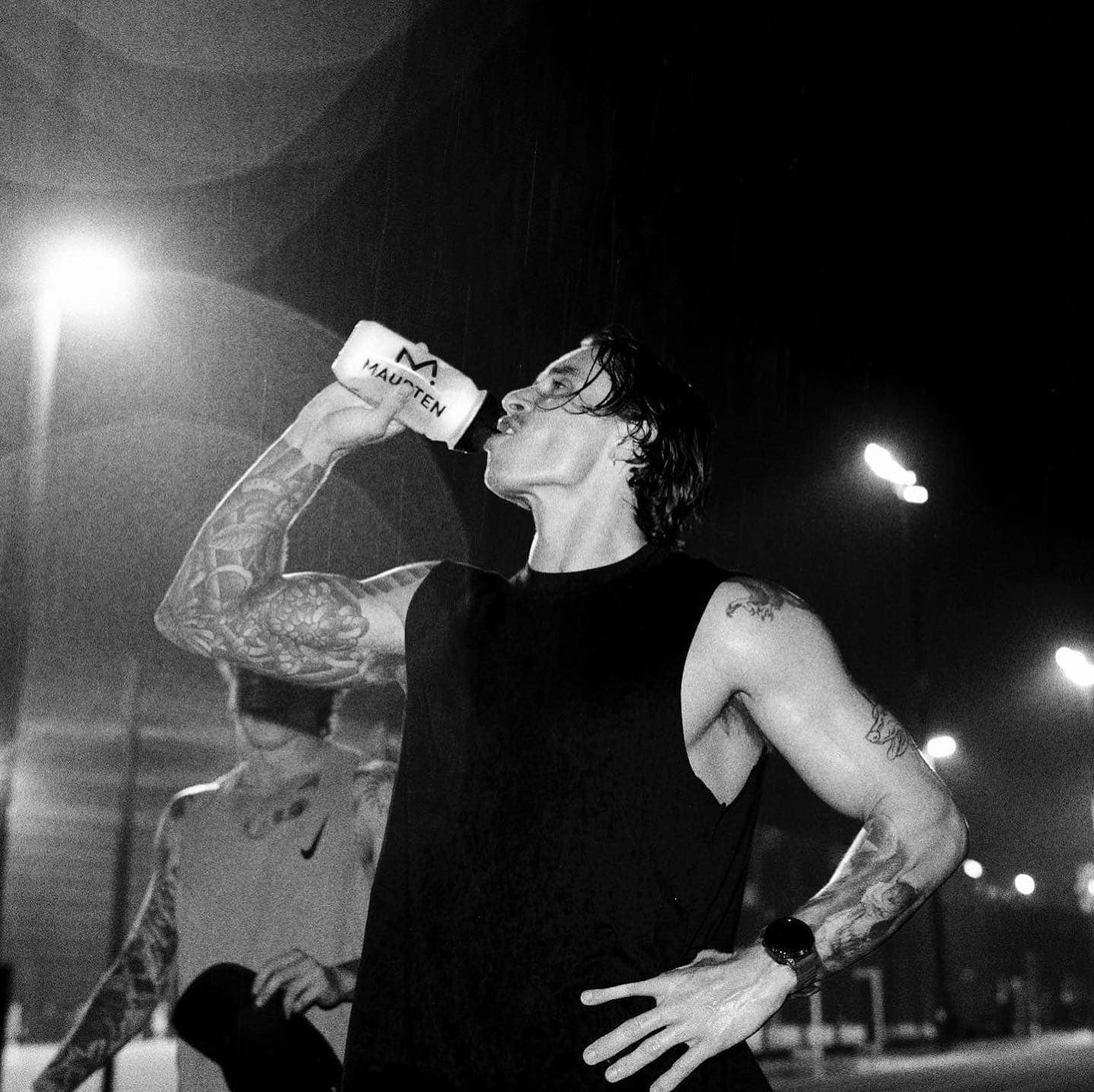 man in black tank top drinking water from a tumbler