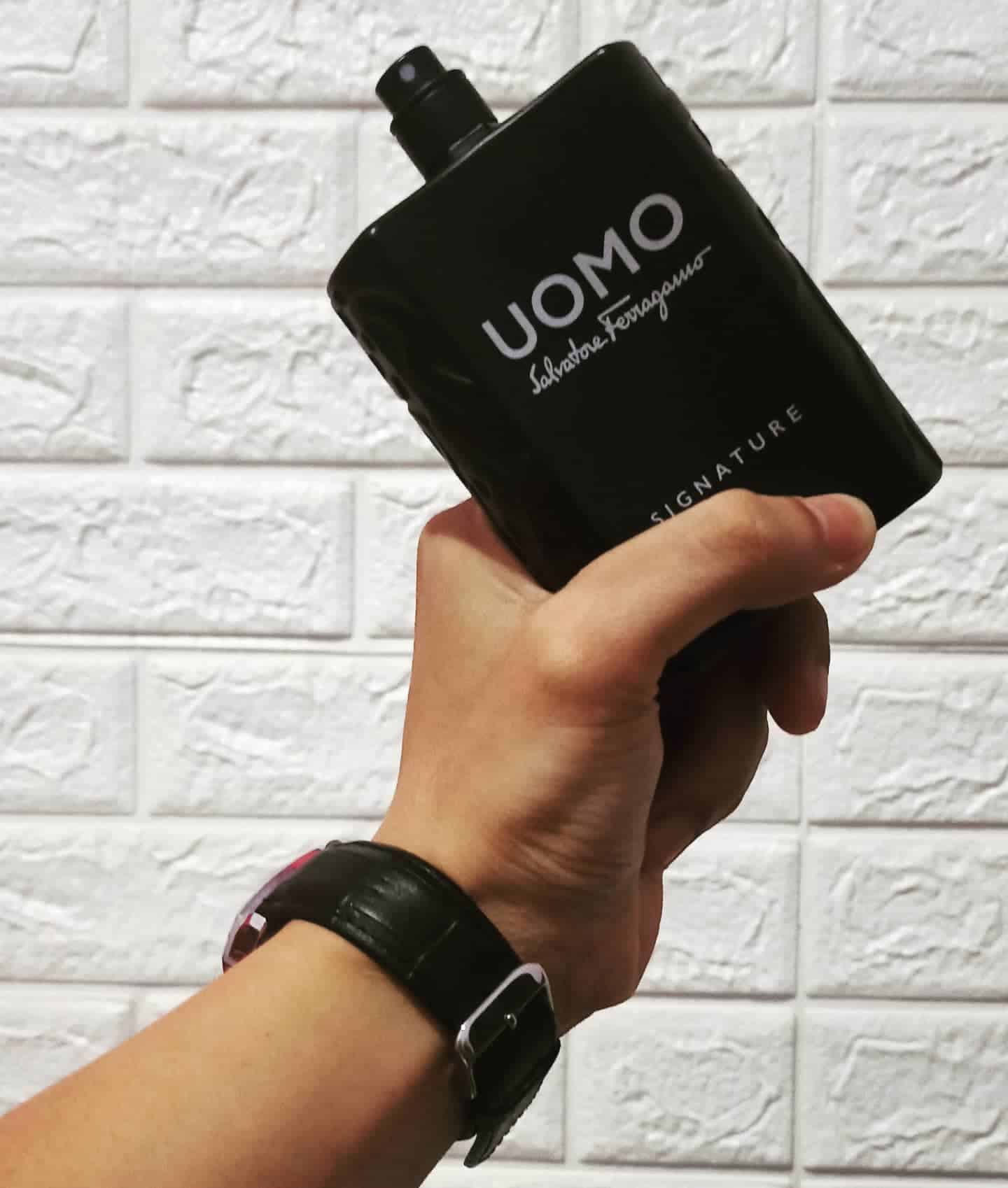 holding a big bottle of uomo signature by salvatore ferragamo