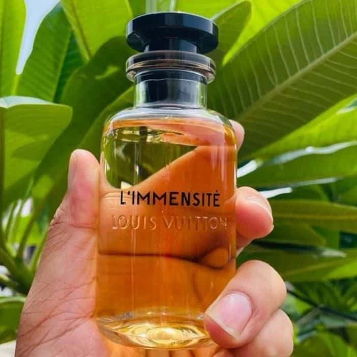 holding a bottle of l'immensite by louis vuitton