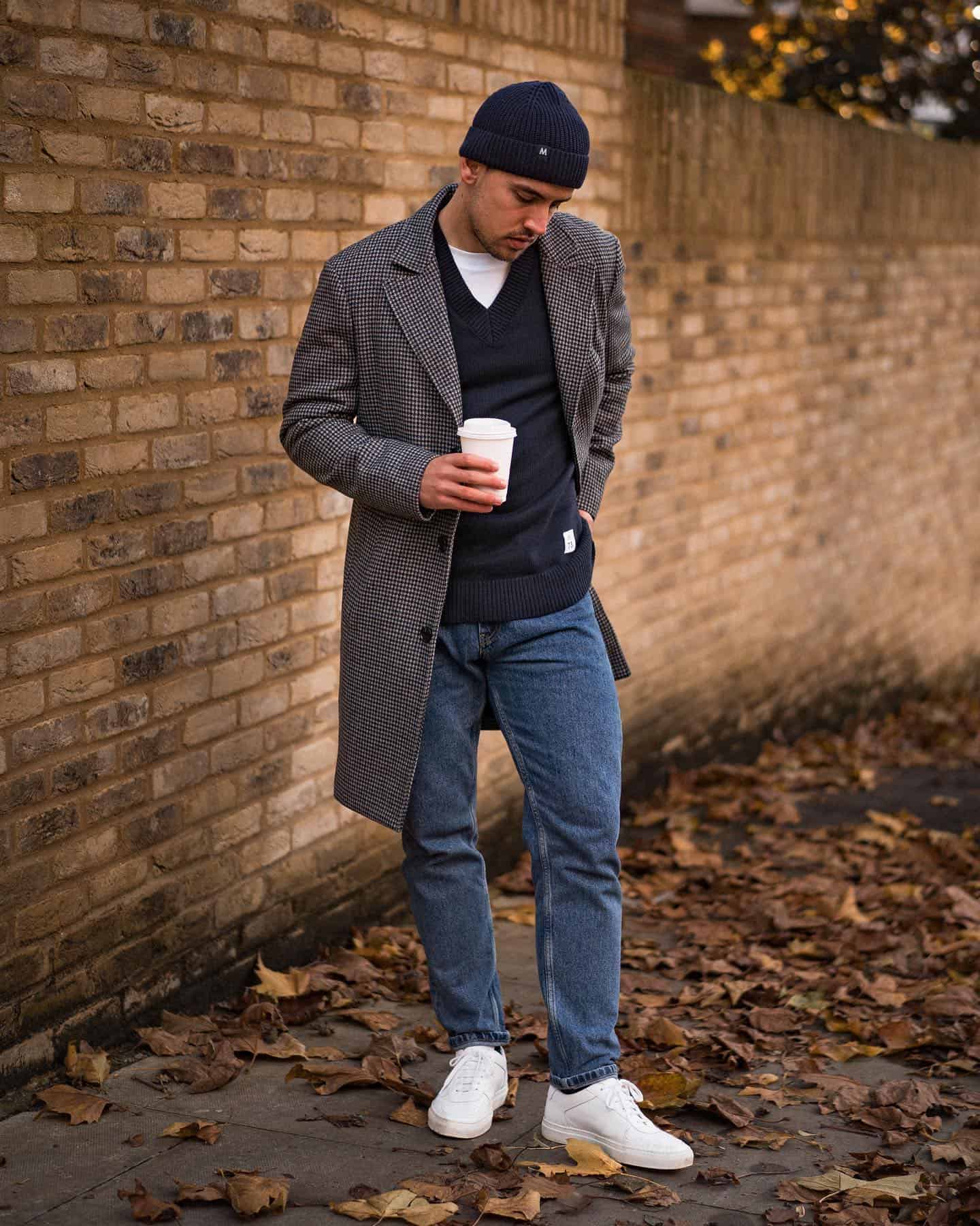 a man in an autumn outfit holding a disposable cup