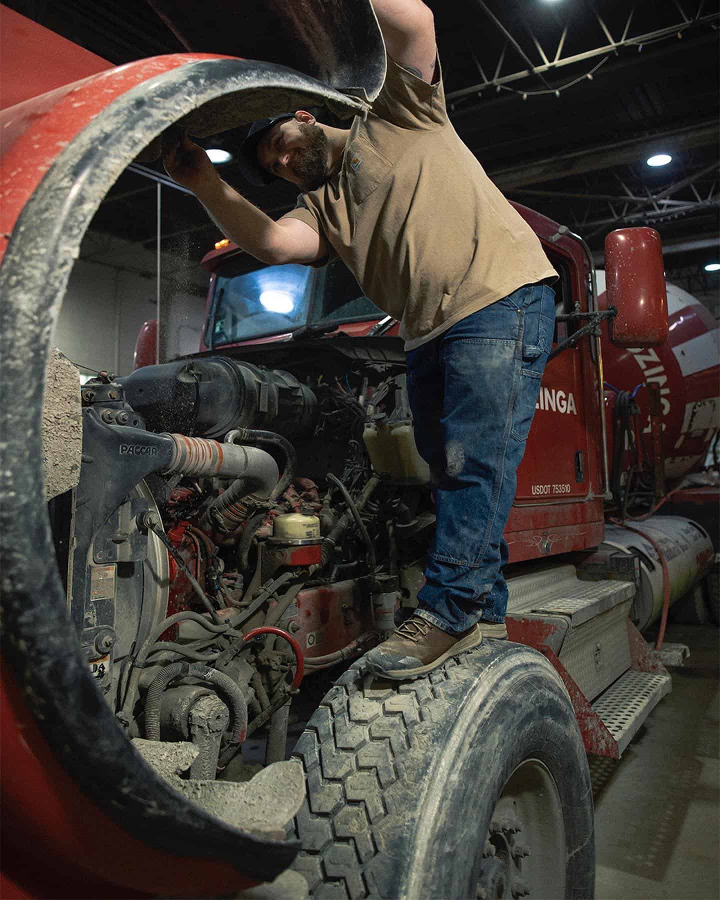 man under the hood of a cement truck