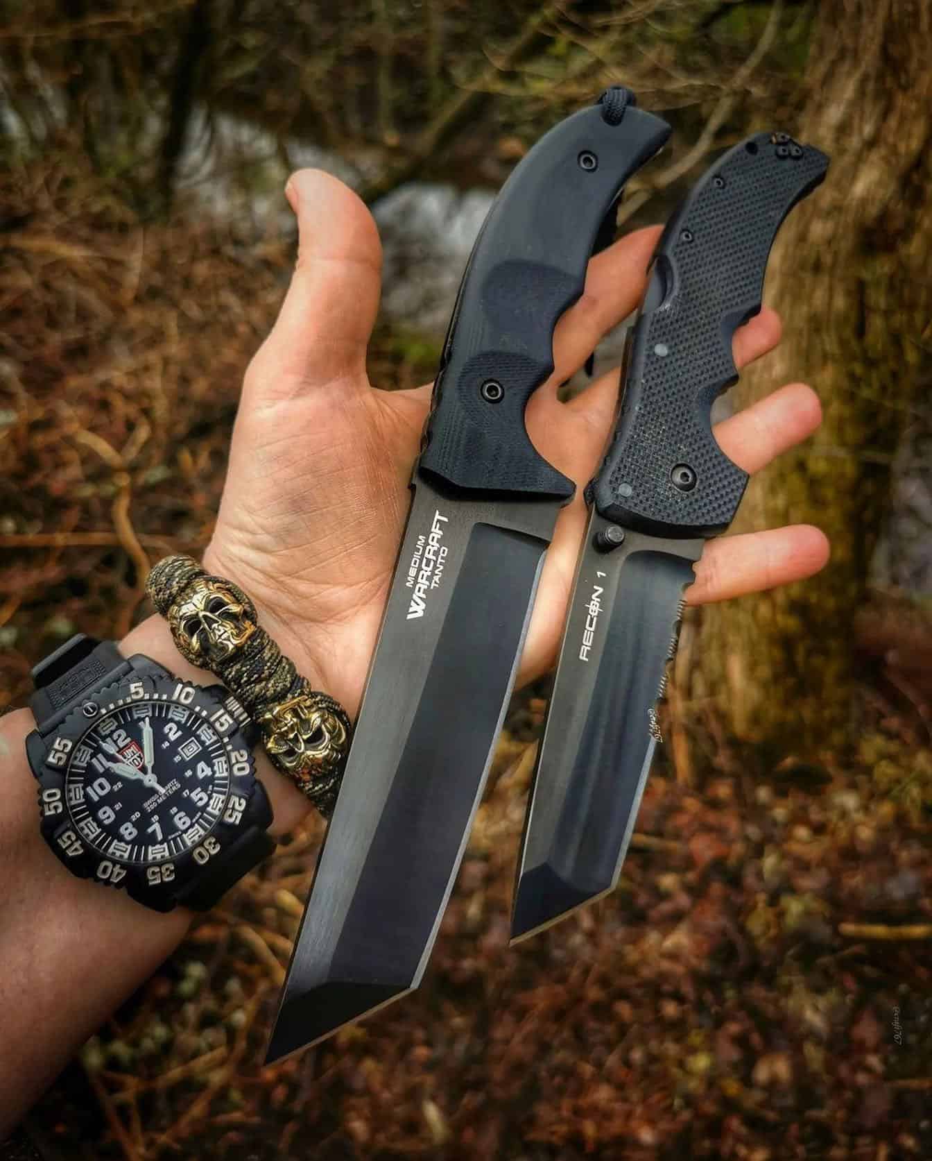 man holding two black finish knives