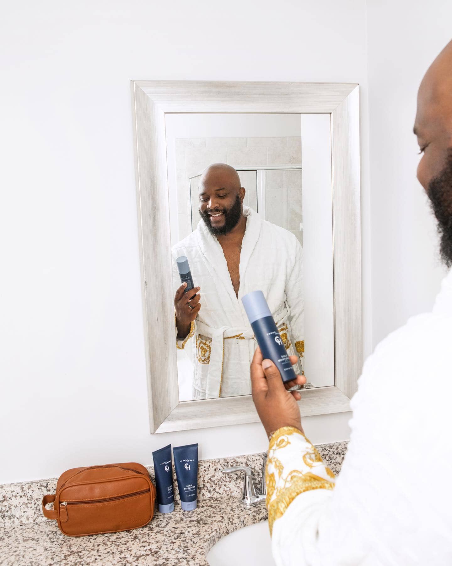 bald man holding a scalp moisturizer by comme homme