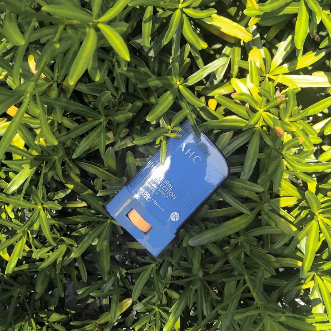 Natural Perfection sunstick by AHC on top of leaves