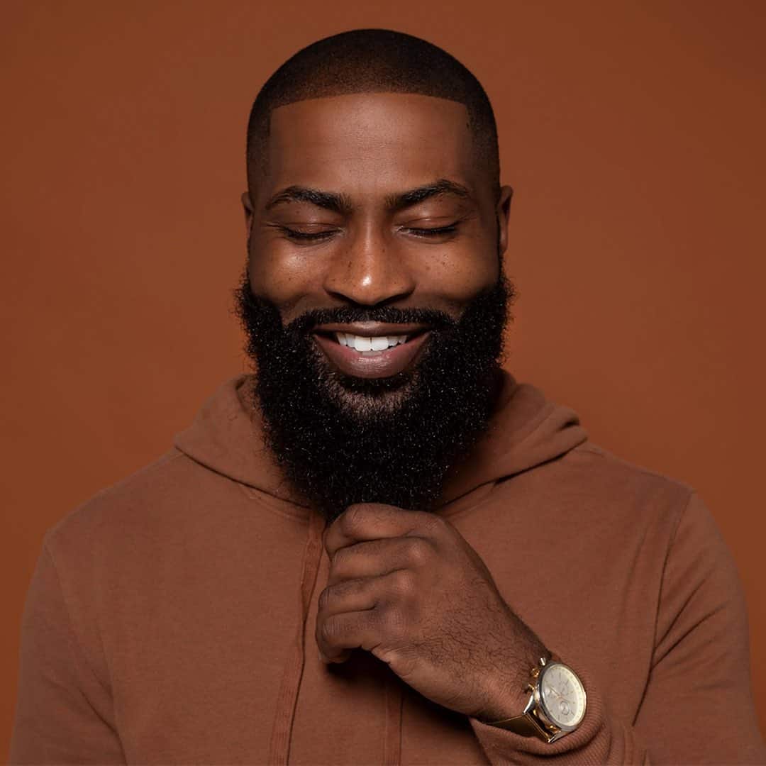 man touching his beard with eyes closed