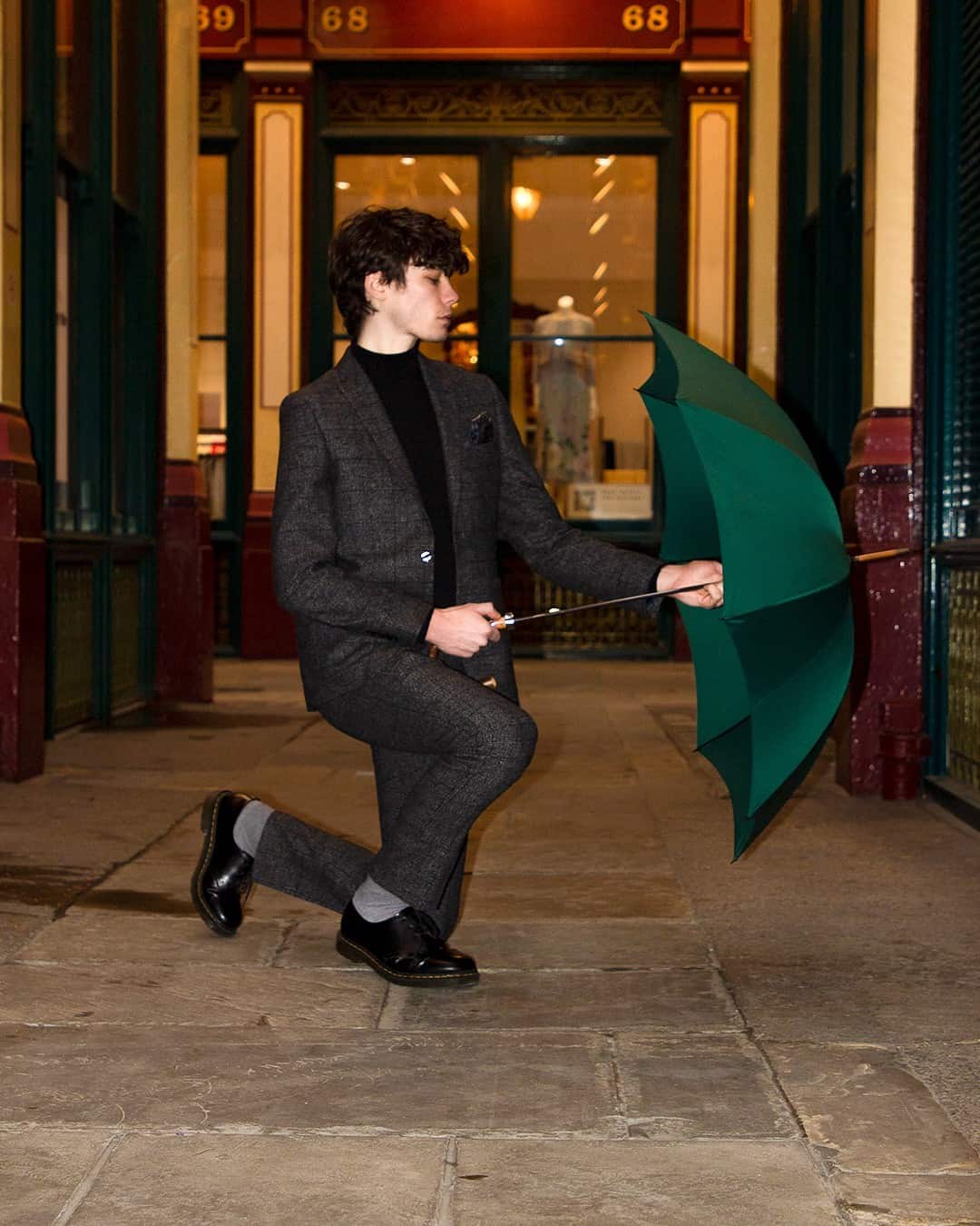 man kneeling on one knee while opening an umbrella