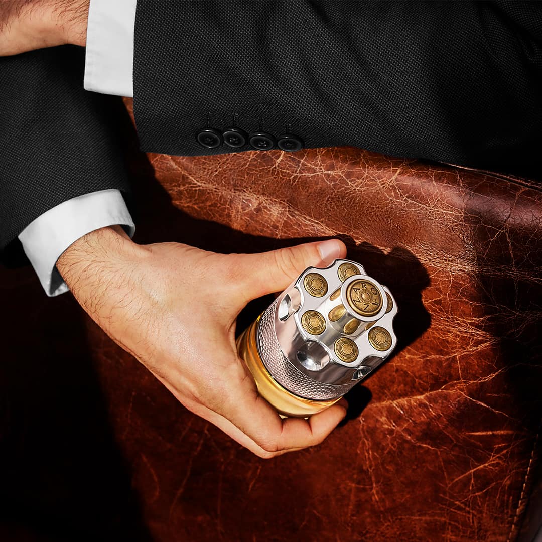 man holding a bottle of azzaro wanted cologne