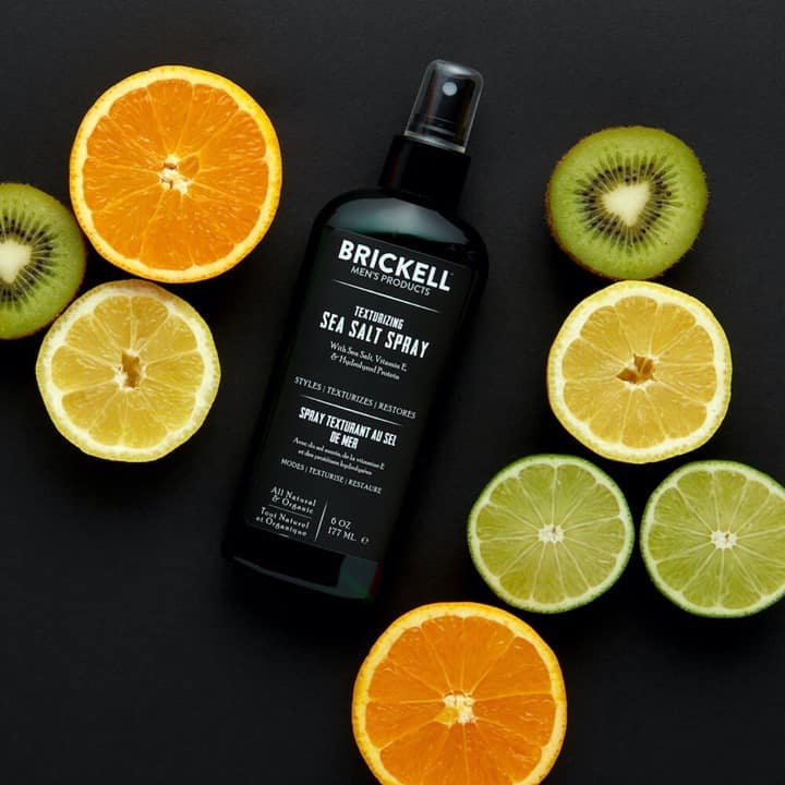 a bottle of sea salt spray by brickell surrounded with slices of fruits