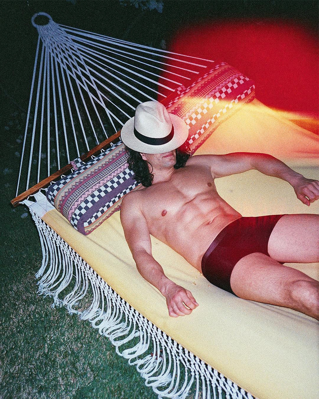man in underwear sleeping on a hammock