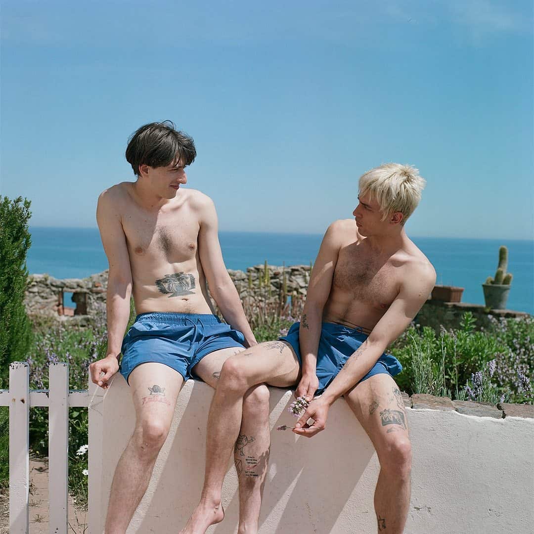 two men having a conversation on top of a concrete fence