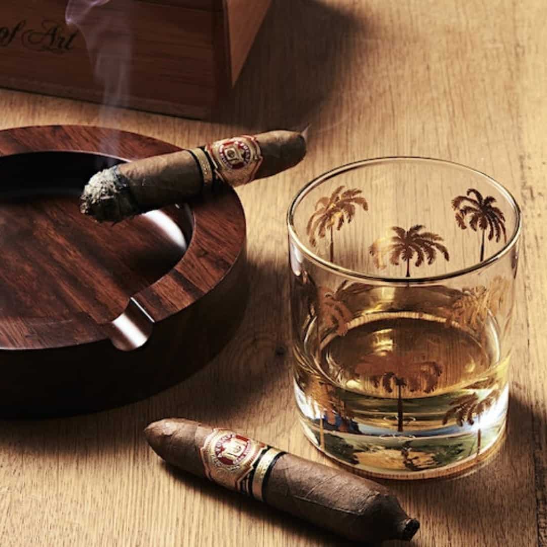 a lit up cigar on a wooden ashtray