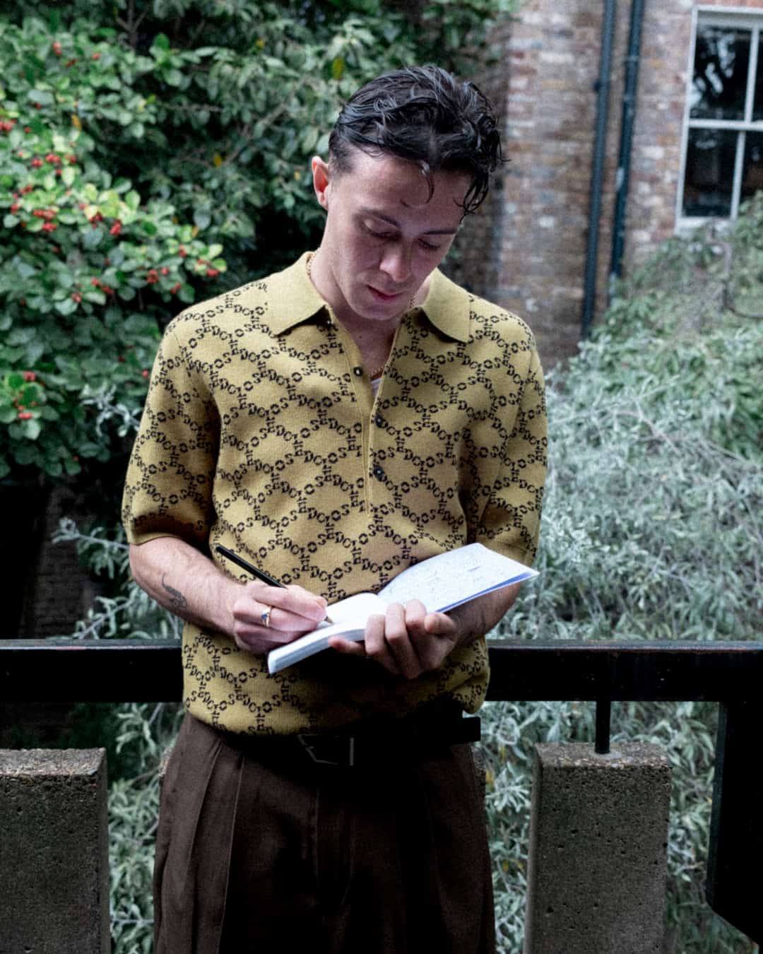 man on a balcony writing on his journal
