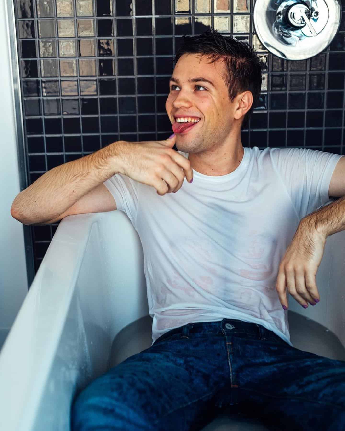 man wearing jeans and shirt in bathtub