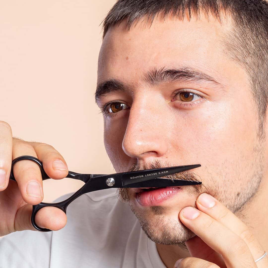 man trimming his mustache with scissors