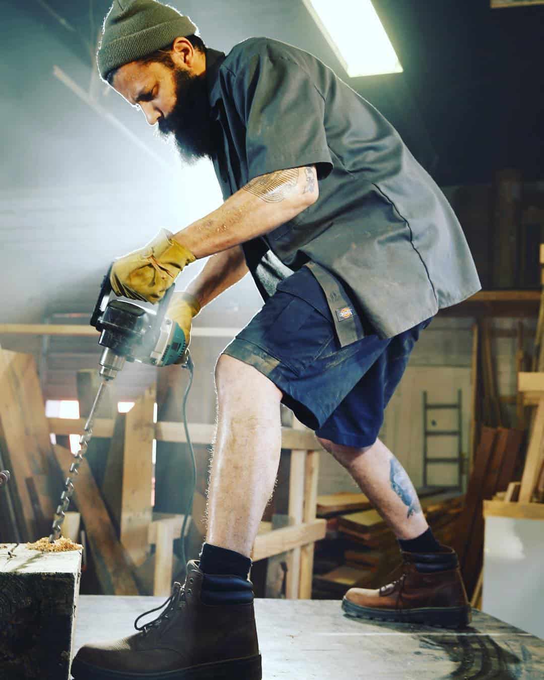 man on top of a table drilling a hole to a wood