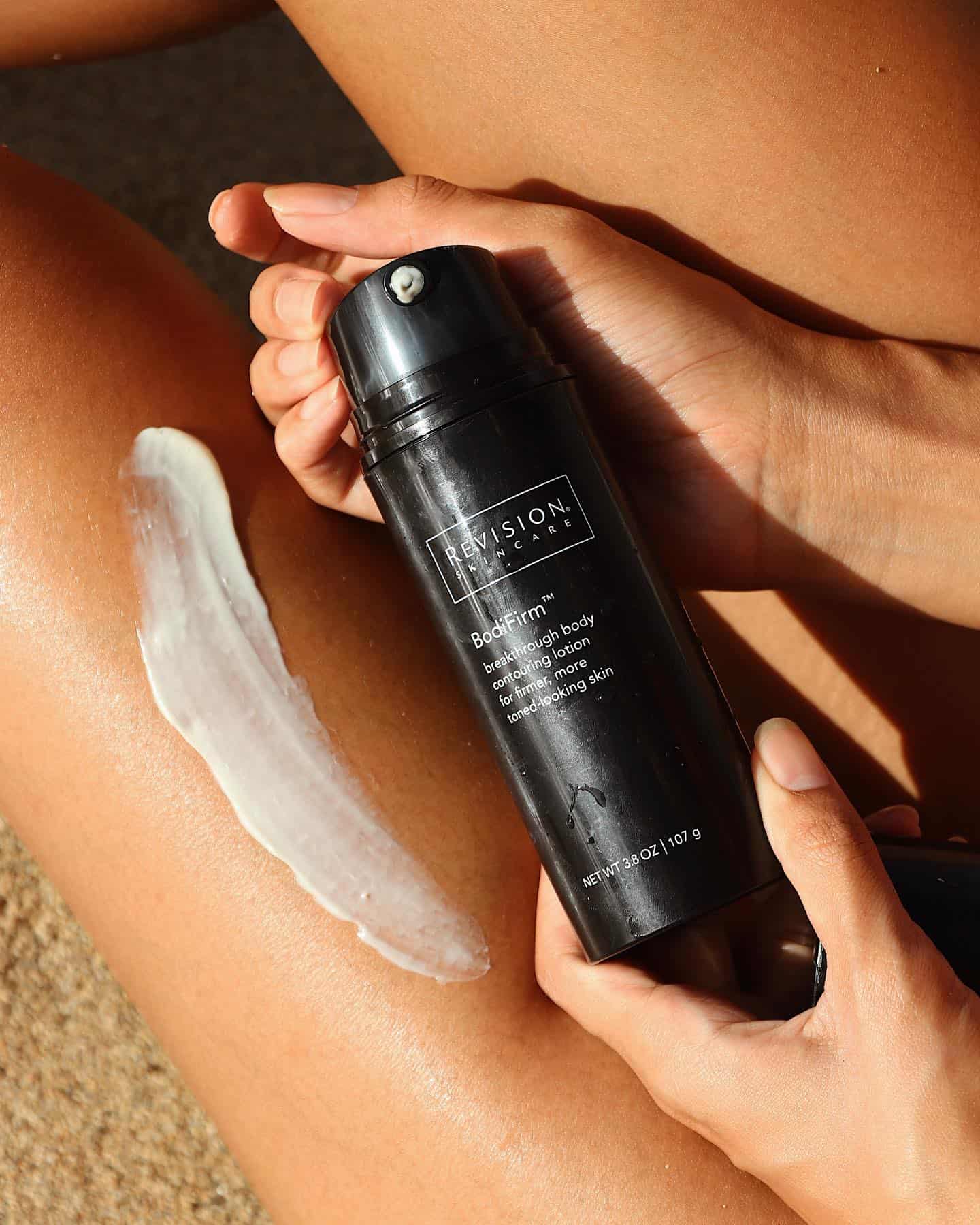 holding a bottle of bodifirm lotion by revision skincare