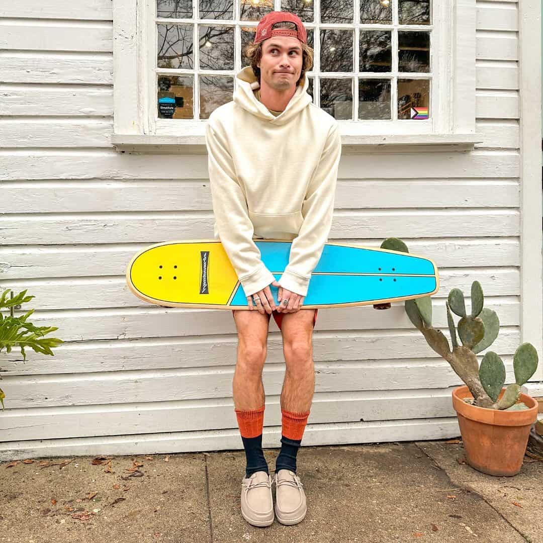man acting silly while holding a long board