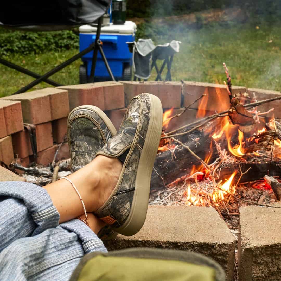 wearing a pair of camo sneakers in-front of a campfire