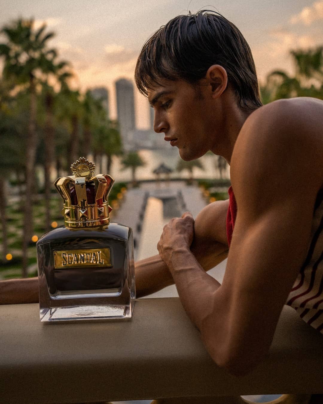 a man and a big bottle of scandal cologne by jean paul gaultier