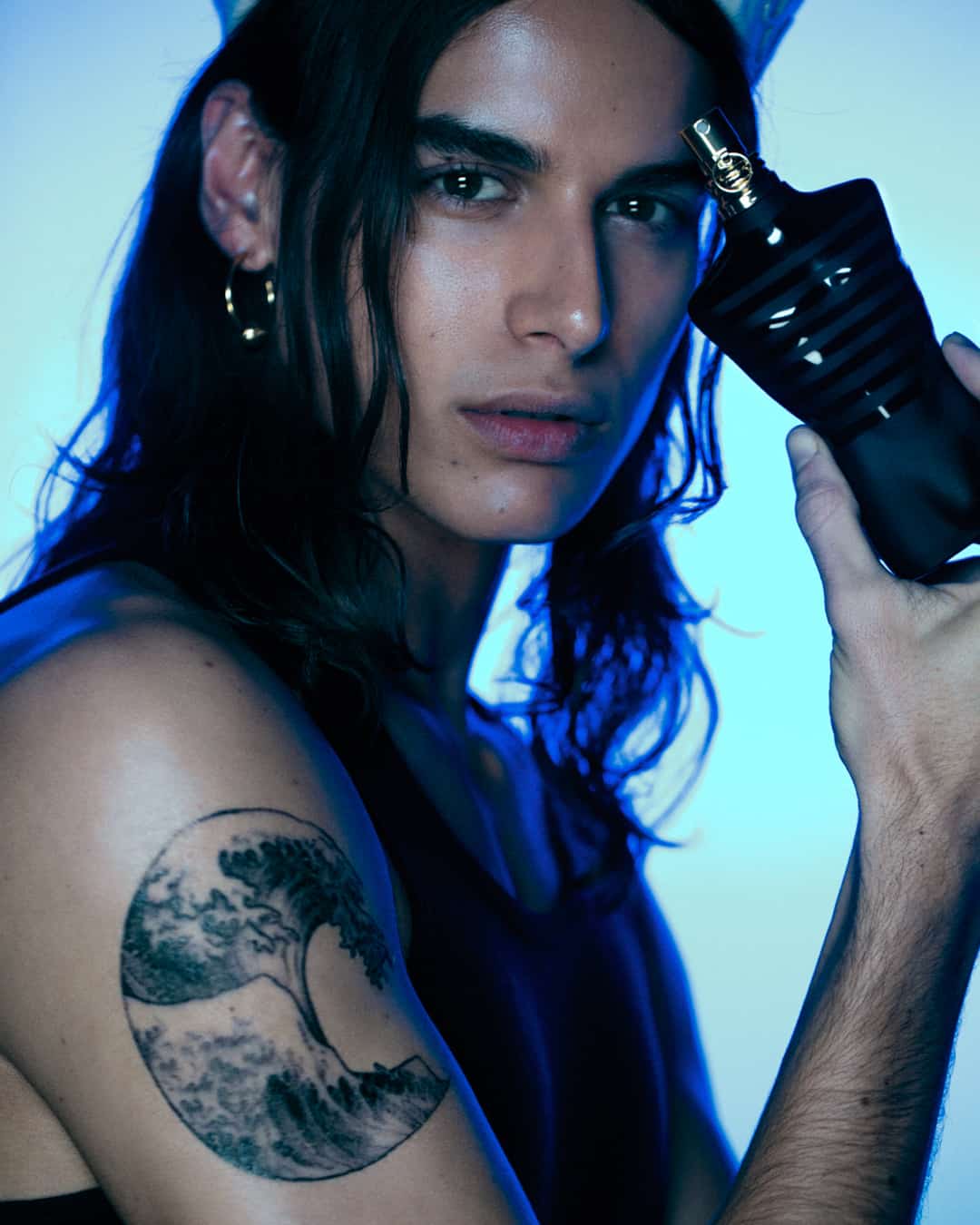man holding a bottle of le male cologne by jean paul gaultier
