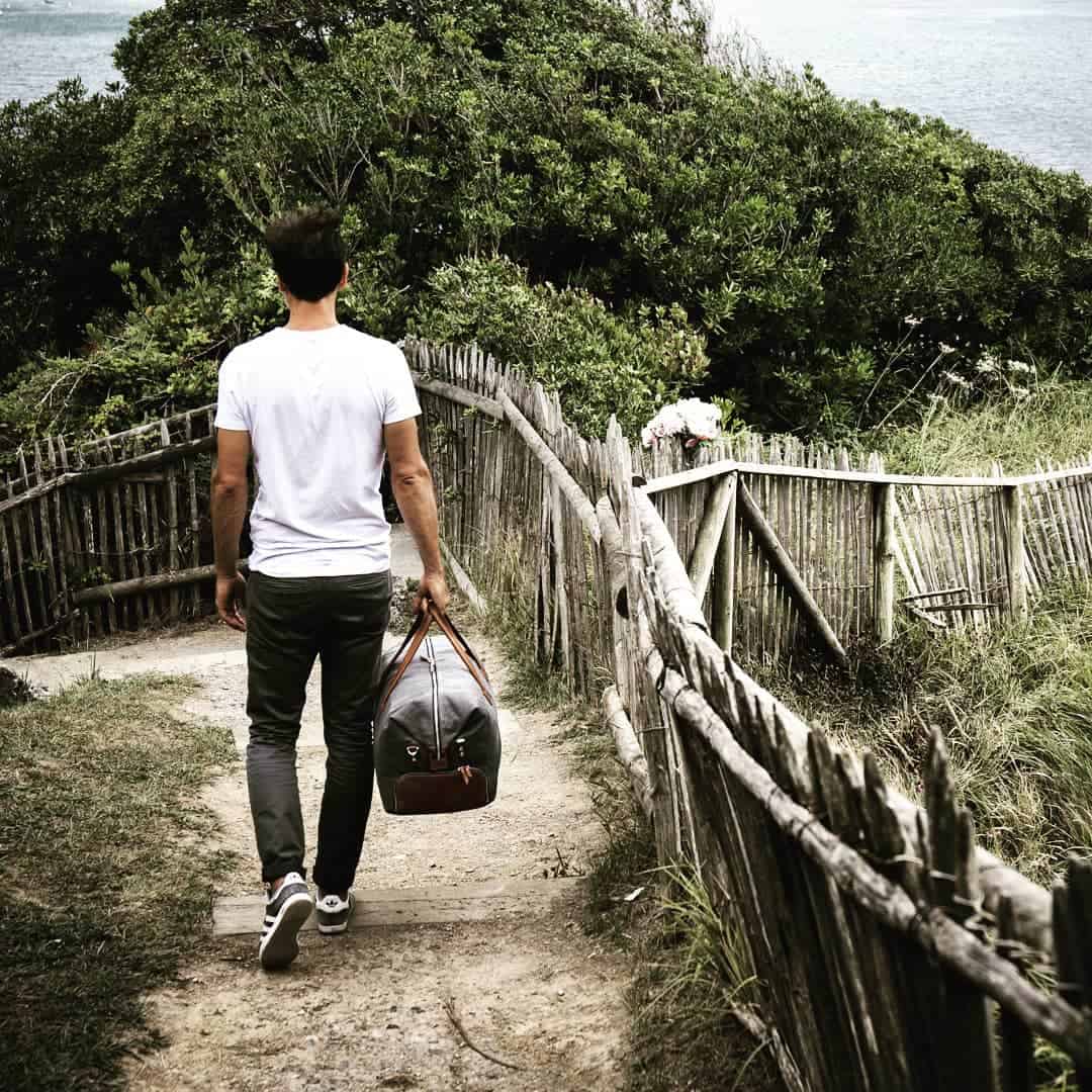 man walking down the hill with a weekender bag
