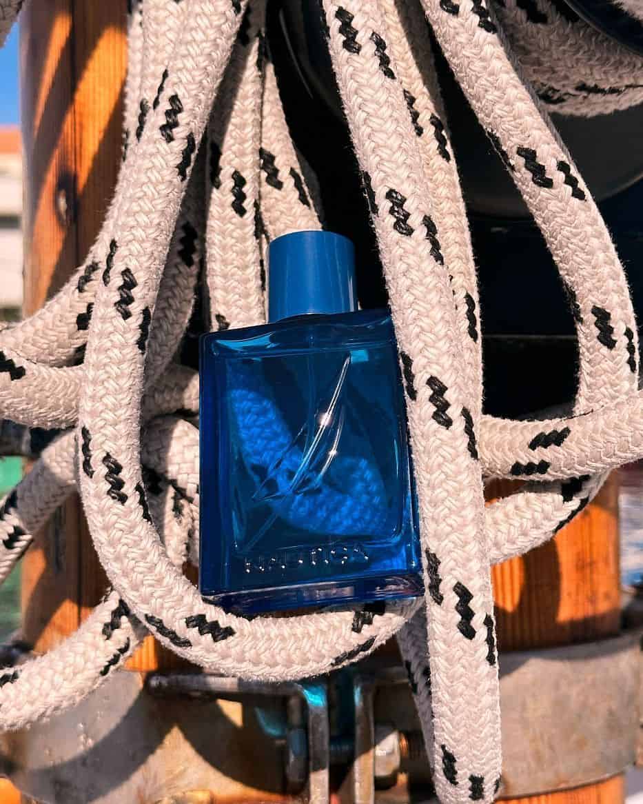 a bottle of nautica cologne sitting on a hanging rope
