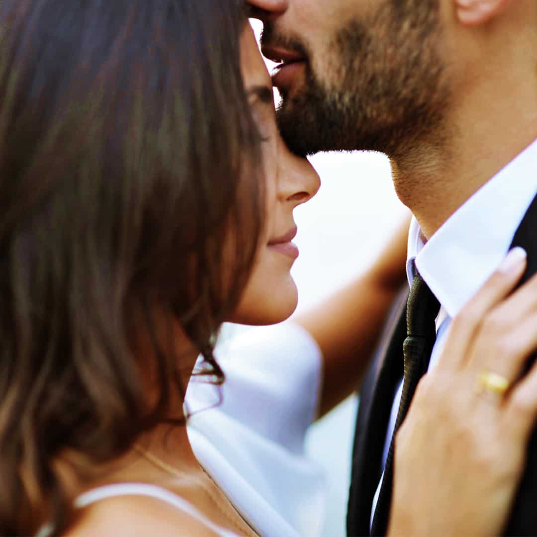man kissing a woman in the forehead