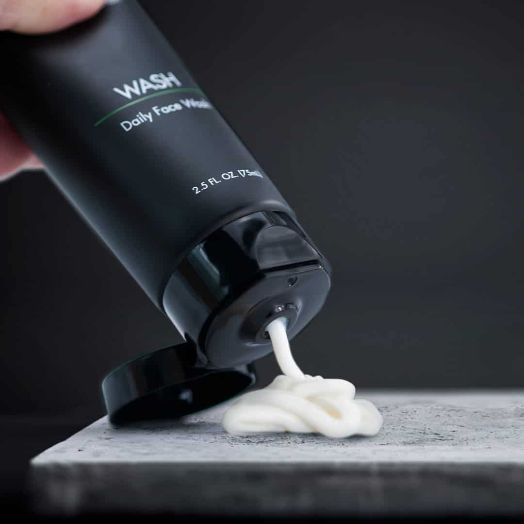 squeezing a tube of daily face wash by tiege hanley