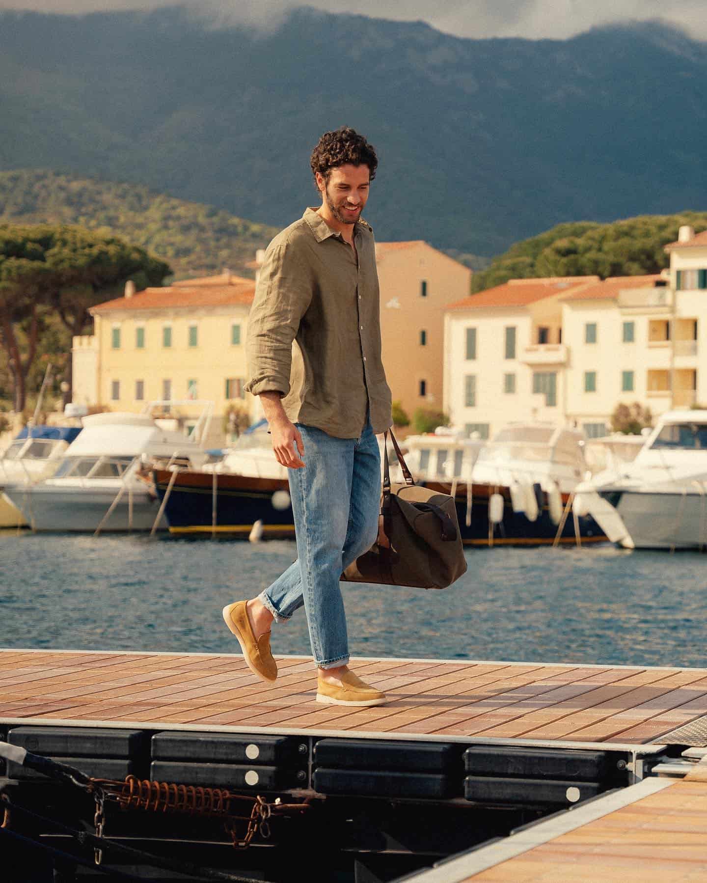 man walking at the docks carrying a weekender bag