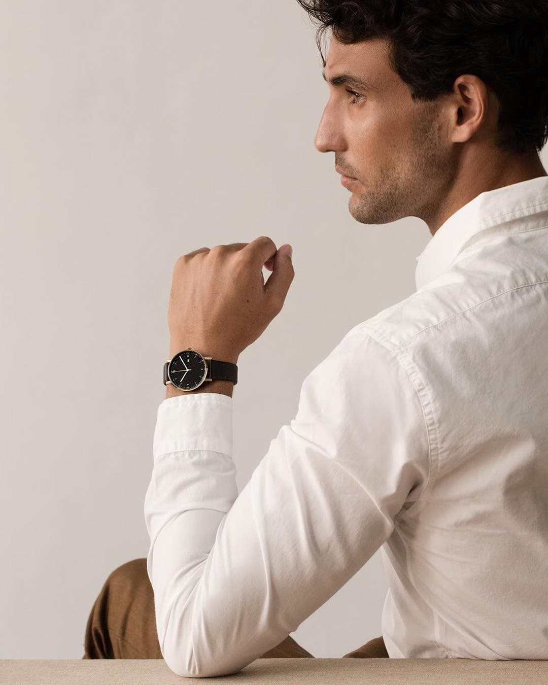 man in white shirt resting his elbow on a table