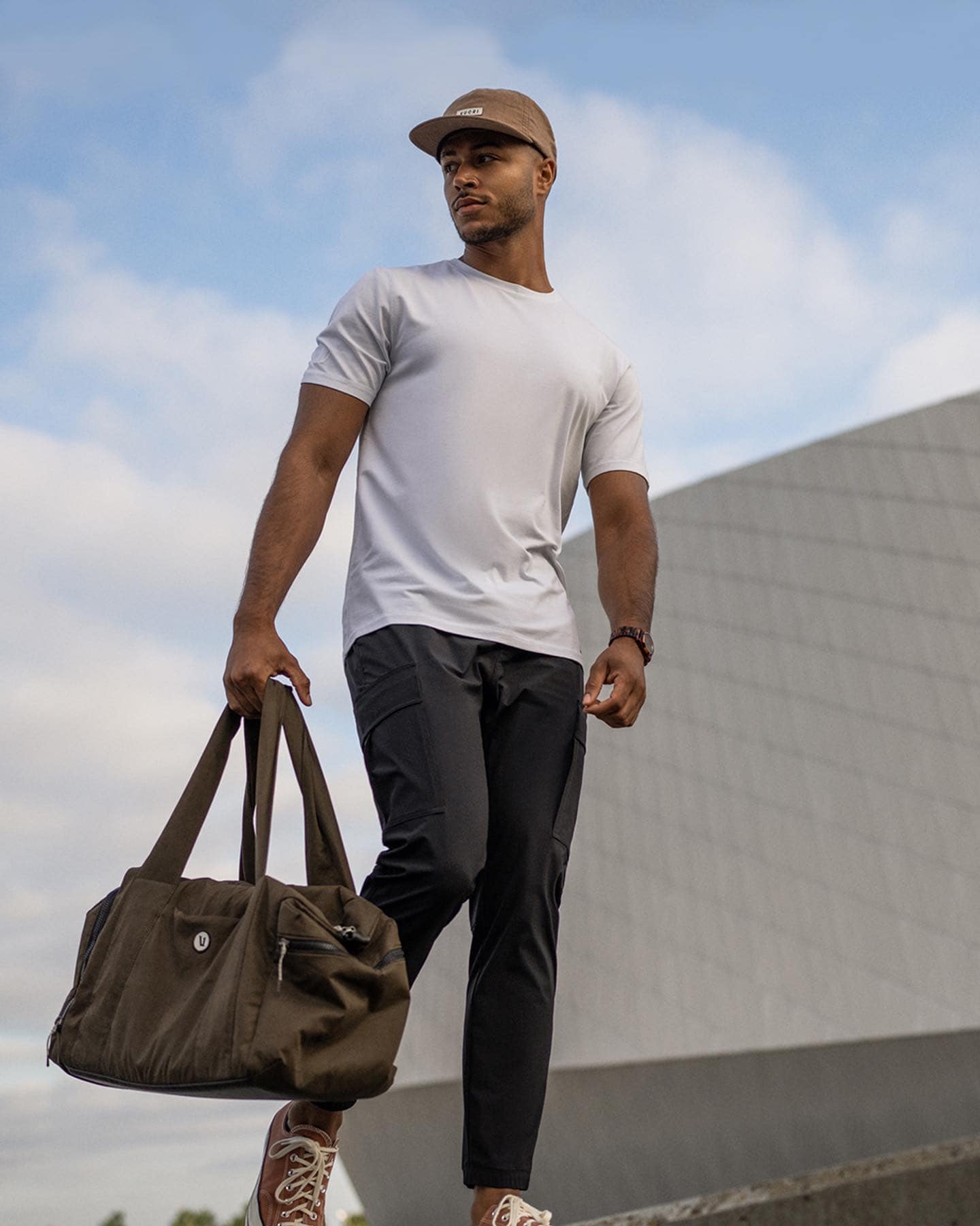 man in white tee carrying a weekender bag