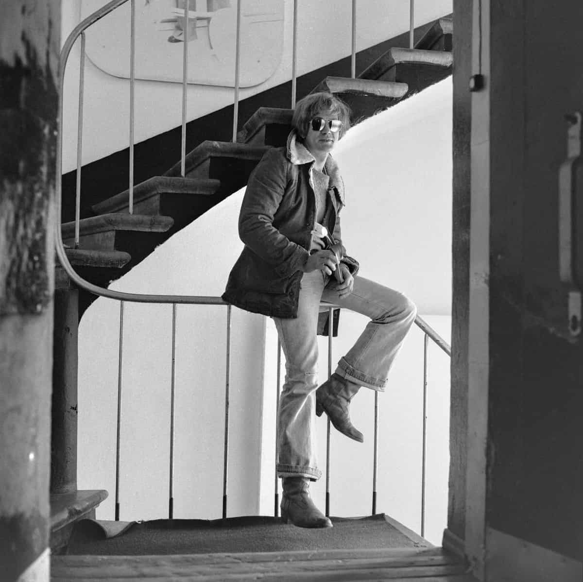 Man in a jacket sitting on the staircase railings