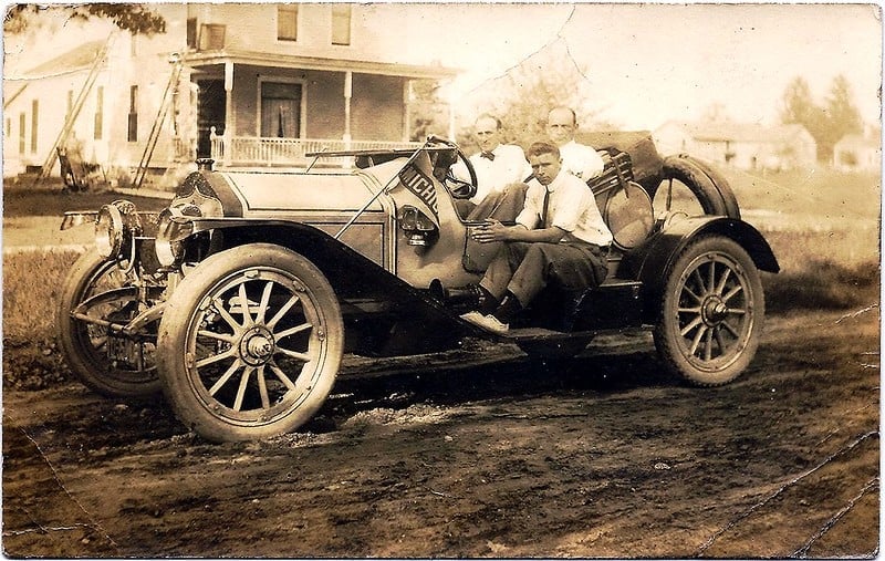 Three unidentified men in open car with University of Michigan pennant, location unknown (rural), 1920s.