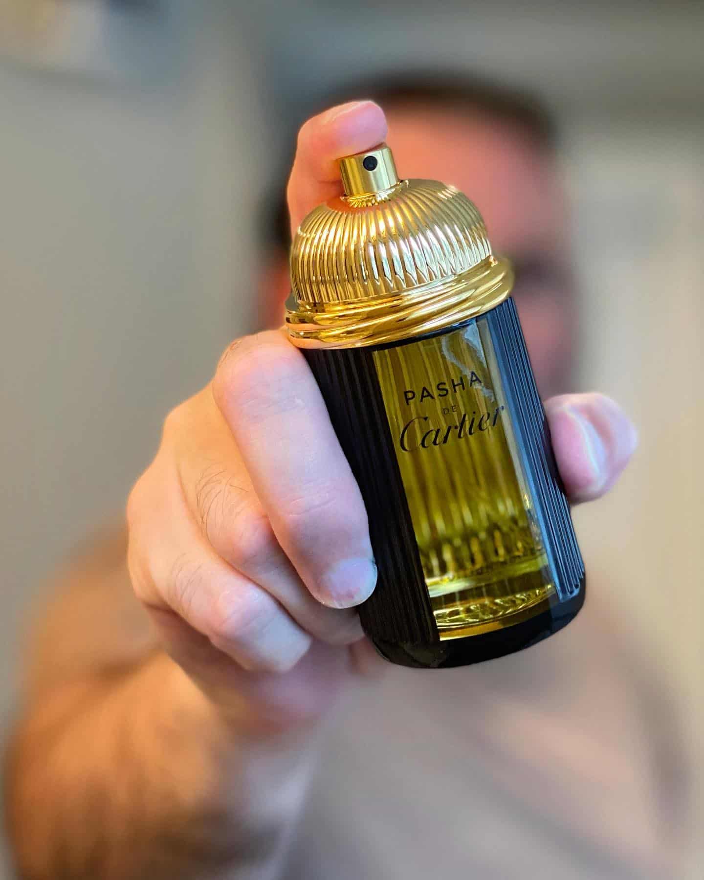 man holding a bottle of pasha de cartier cologne