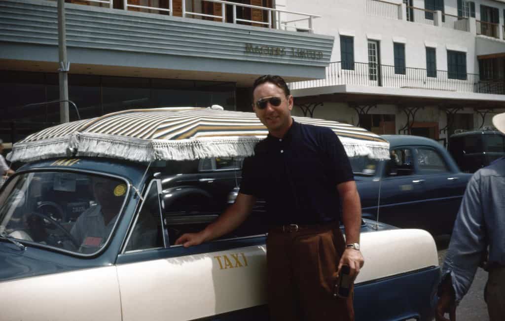 Man in 1950s standing beside a taxi