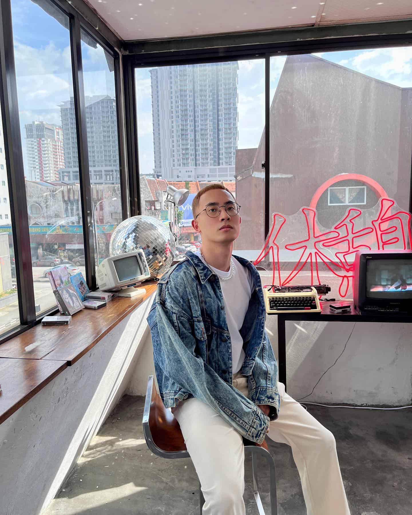 man in a denim jacket sitting on a chair