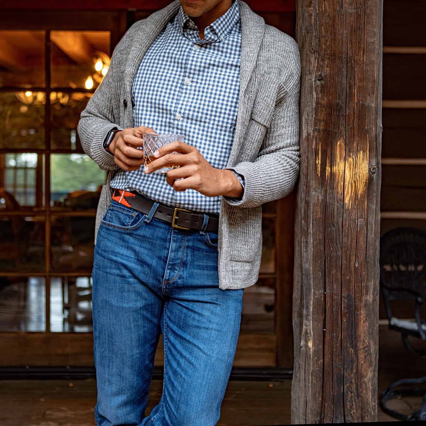 man leaning on a post while holding a glass