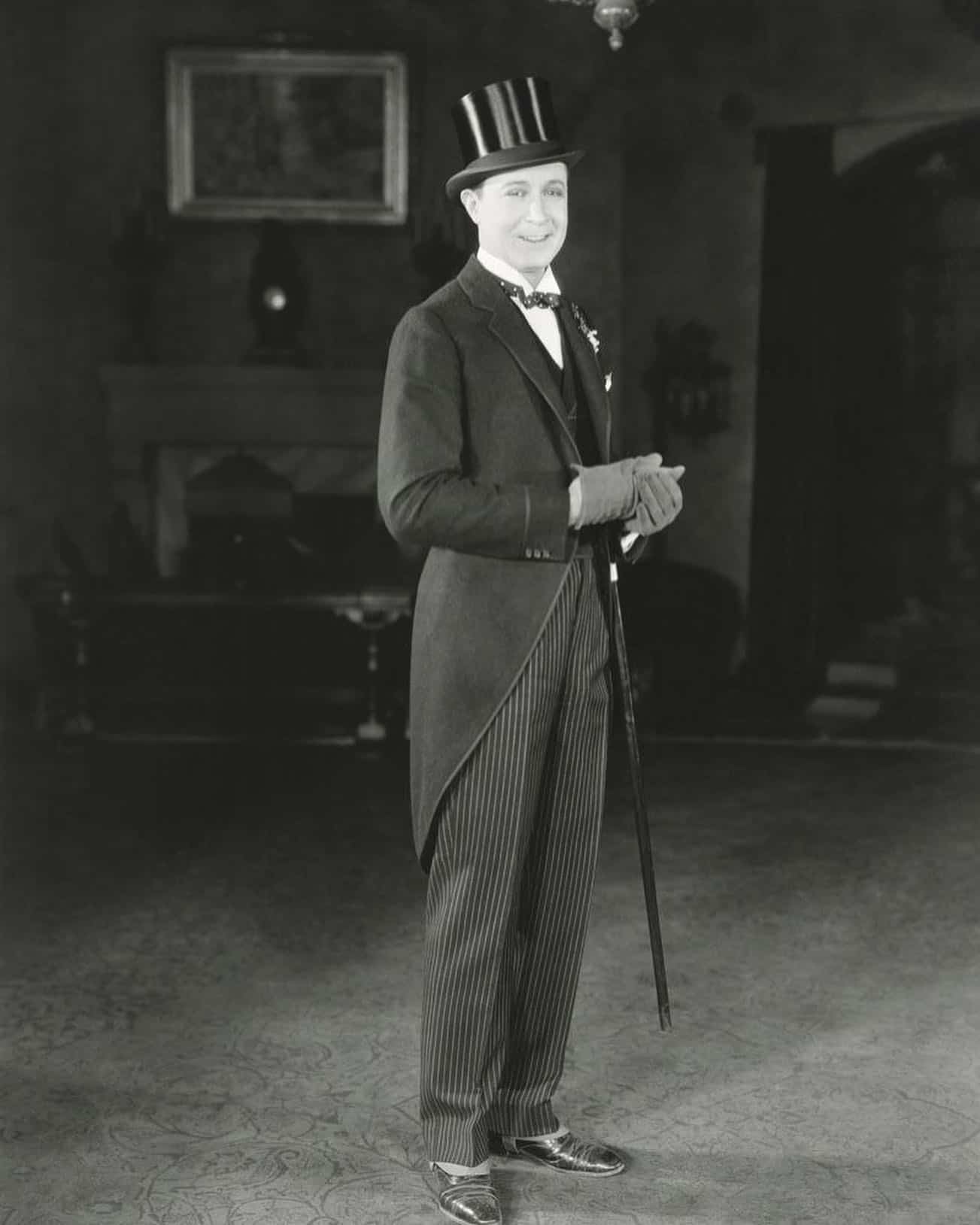 man in 1920s wearing a penguin suit with a hat and a cane