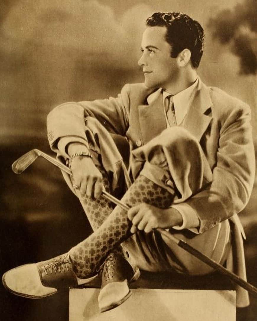 man in 1920s wearing a suit holding a golf club
