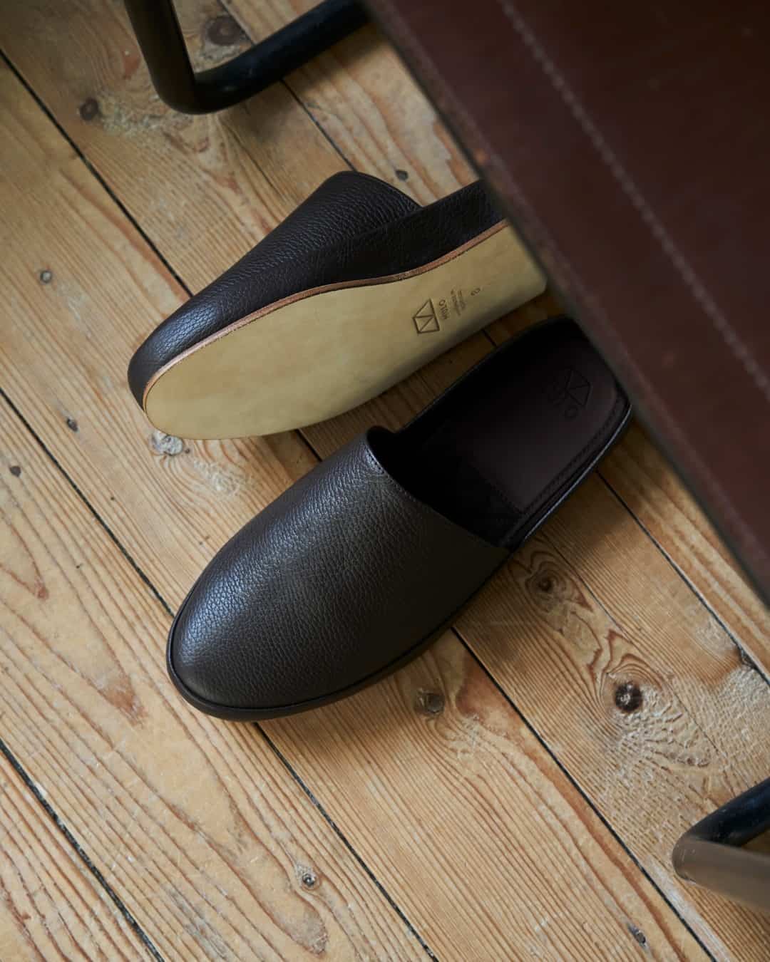 a pair of black leather slipper under a chair