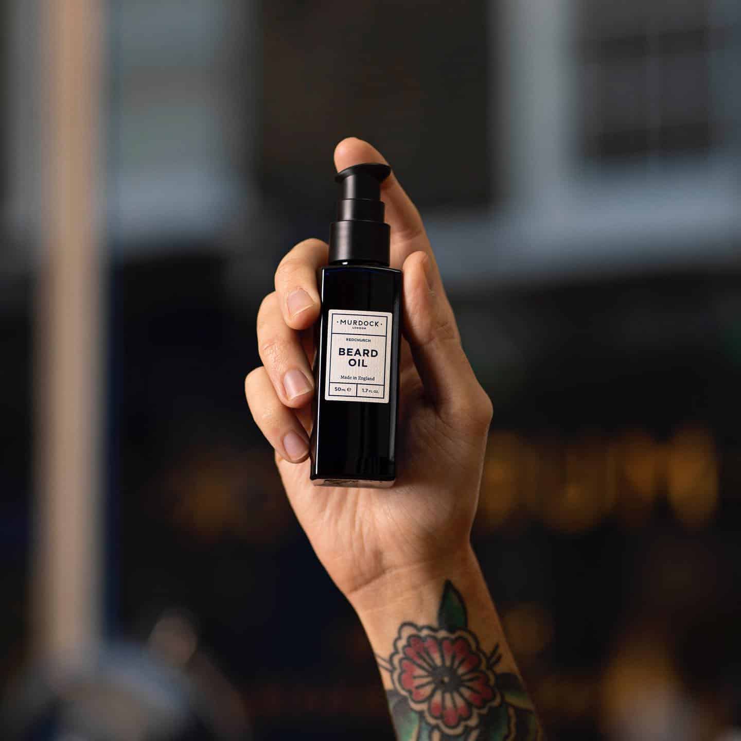holding a bottle of beard oil by murdock london