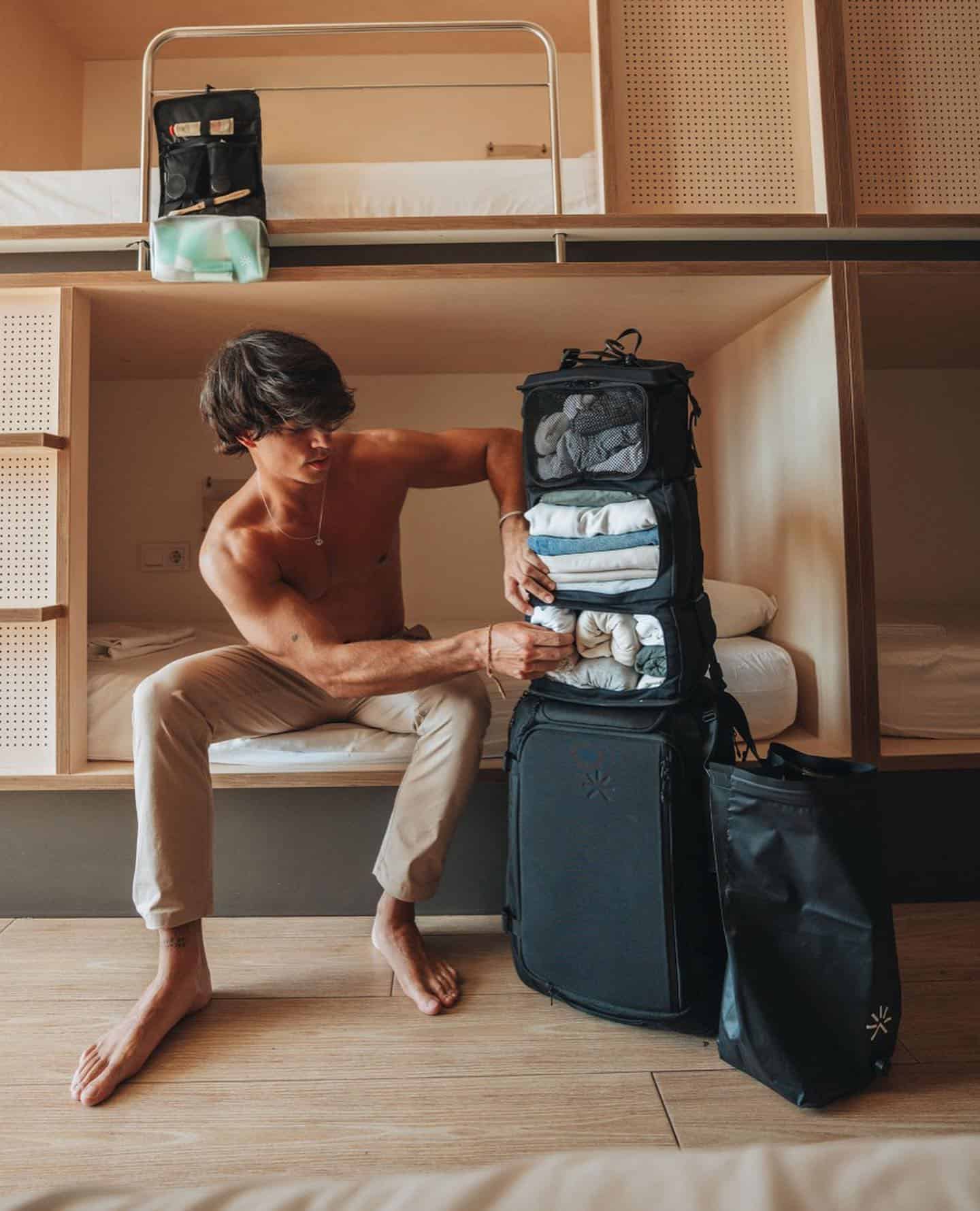 man stuffing clothes into a luggage bag