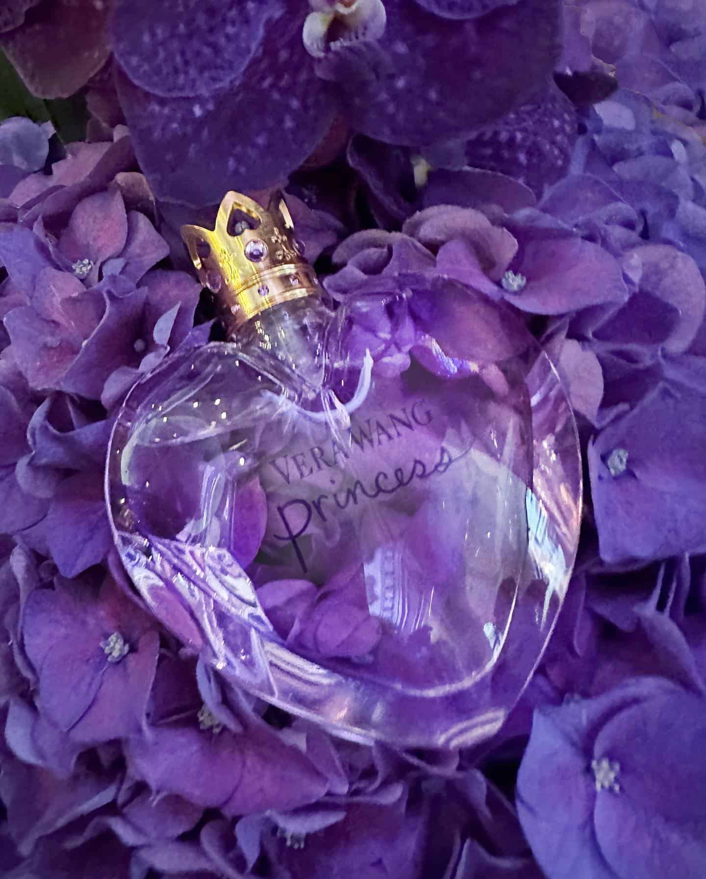 a bottle of princess cologne by vera wang on top of purple flowers