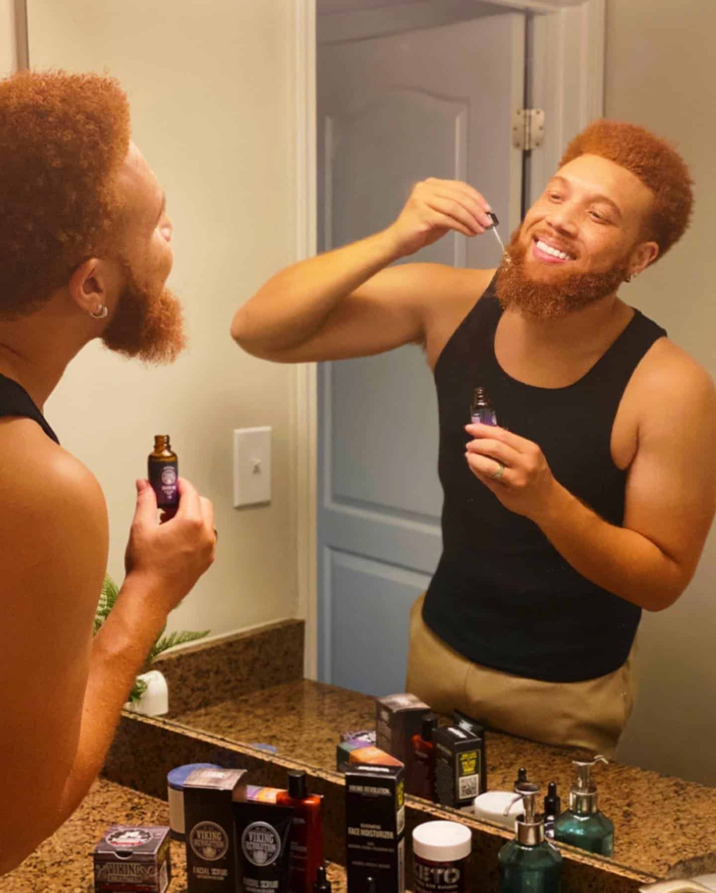 man in tank top using a beard oil by viking revolution