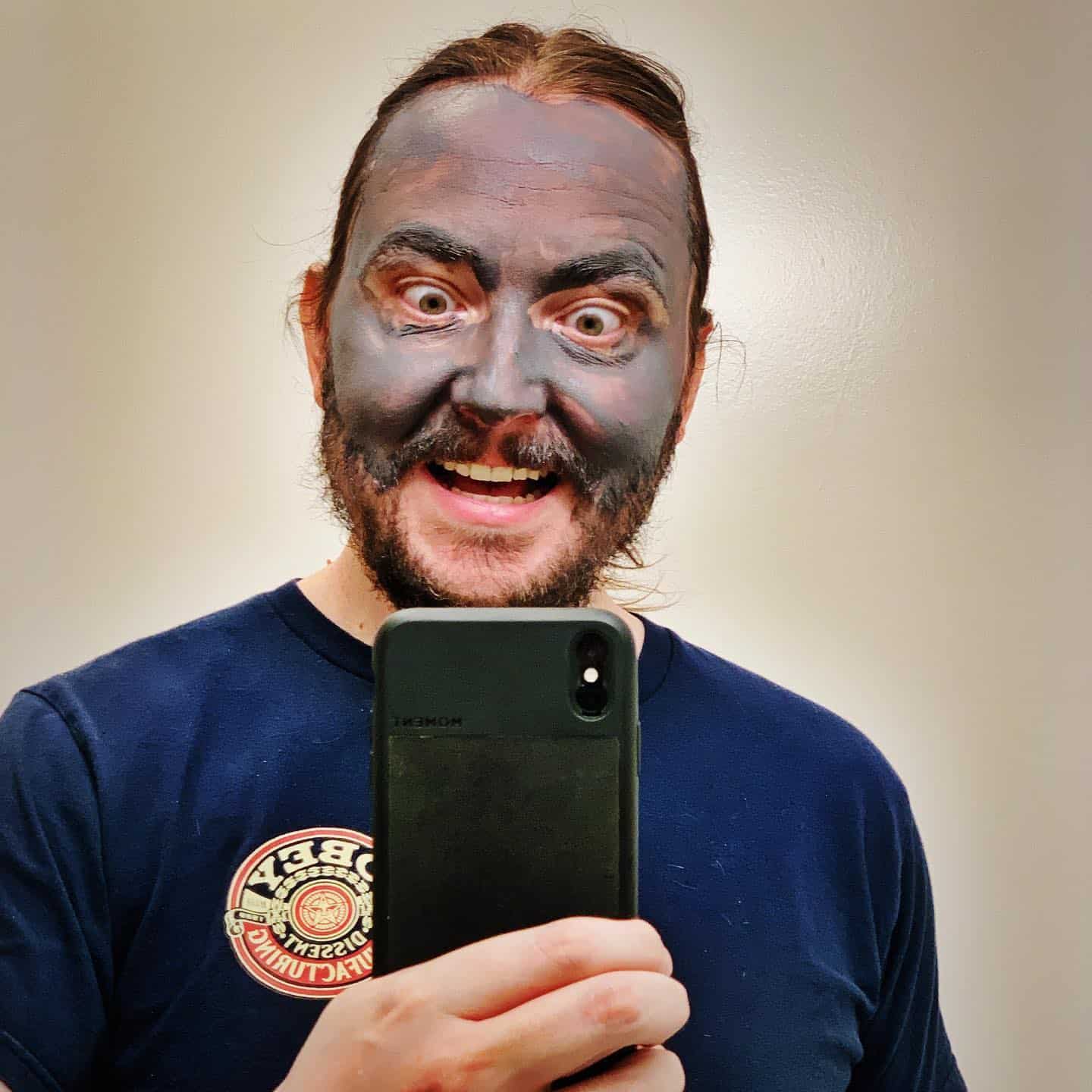 man acting silly with mud mask on face