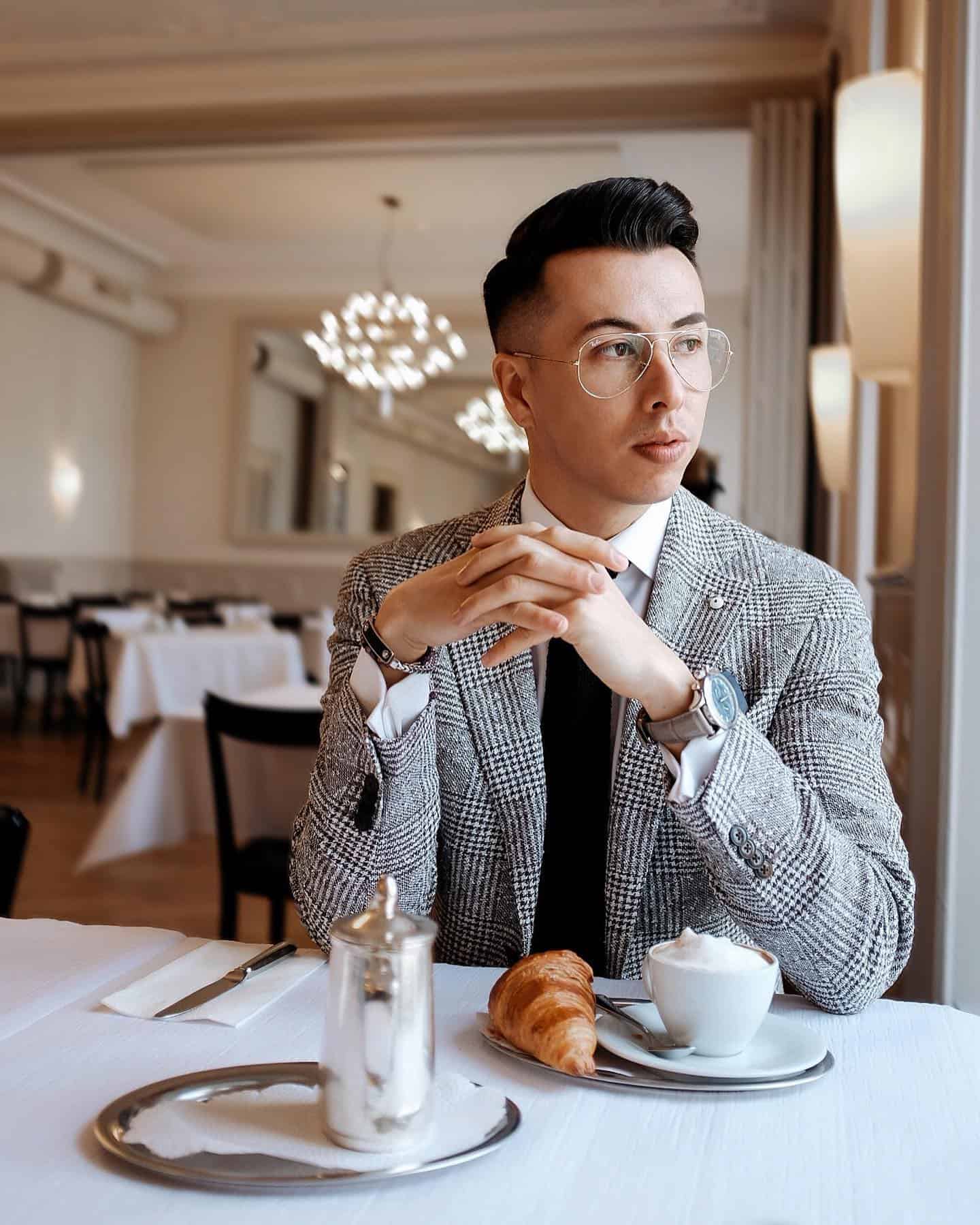 man in a prince of wales checked blazer sitting at a table