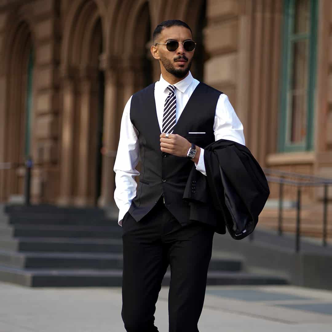 man in a vest carrying suit jacket by the elbow