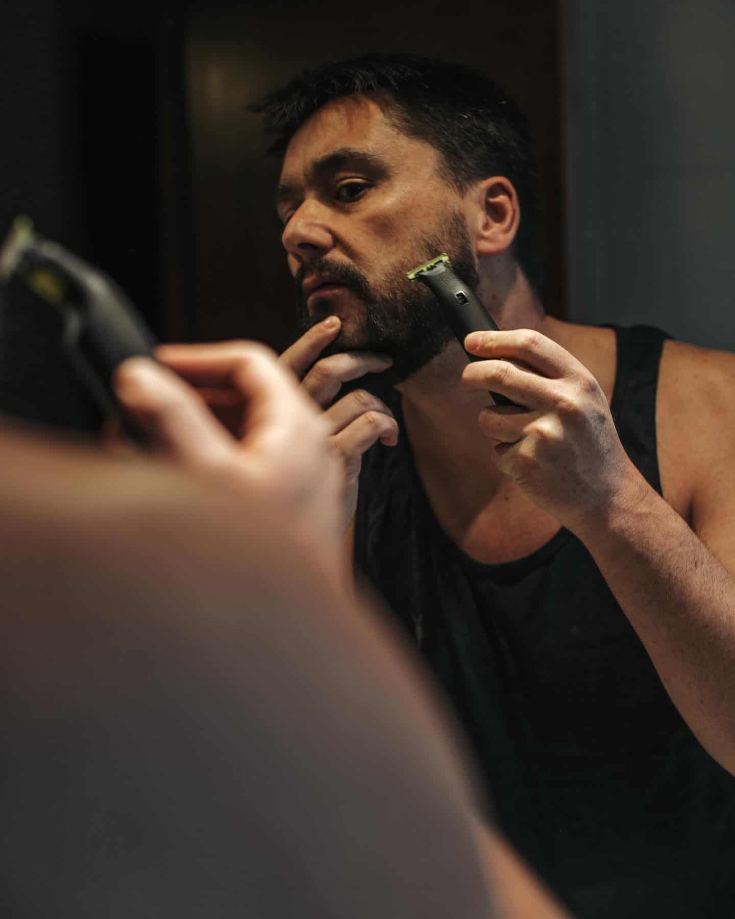 man shaving his beard in-front of the mirror