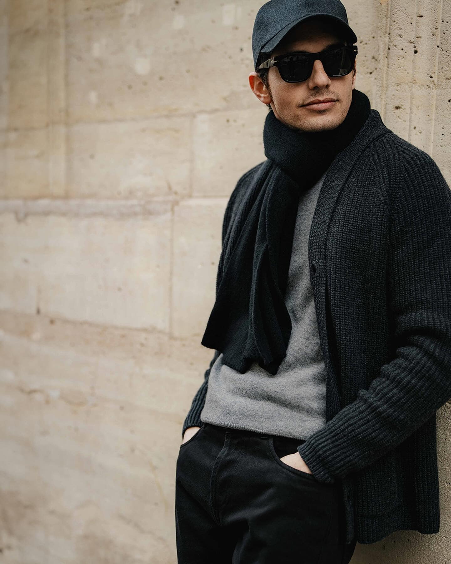 man with sunglasses wearing a cap, scarf and cardigan