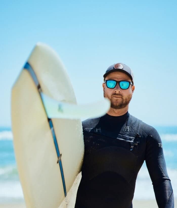 man in sunglasses carrying a surfboard